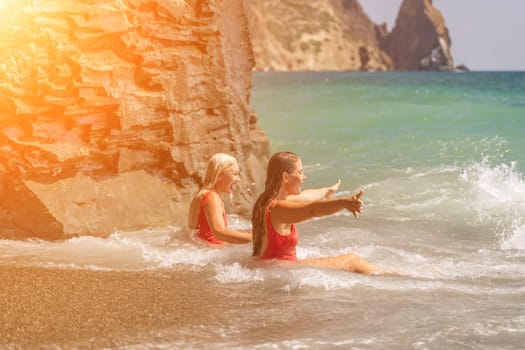 Women ocean play. Seaside, beach daytime, enjoying beach fun. Two women in red swimsuits enjoying themselves in the ocean waves