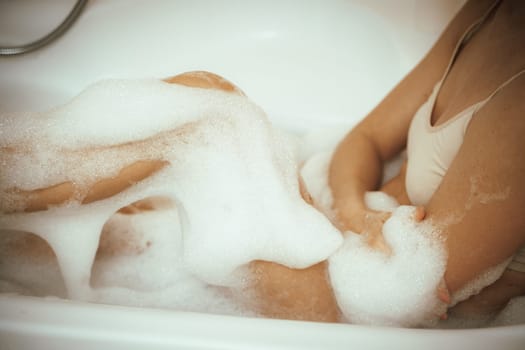 Women's feet in bath foam. View from above. Enjoy and relax in a spa hotel.