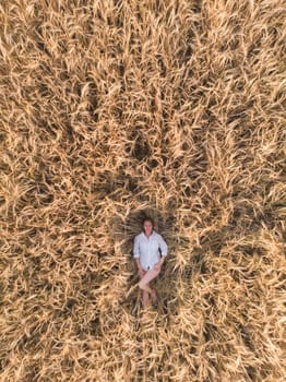 Aerial view of woman lying in the yellow field of wheat