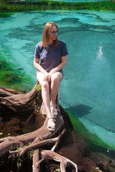 Woman at Beautiful Geyser lake with thermal springs that periodically throw blue clay and silt from the ground. Altai mountains, Russia