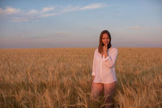 Woman in the yellow field of wheat, beauty summer sunset