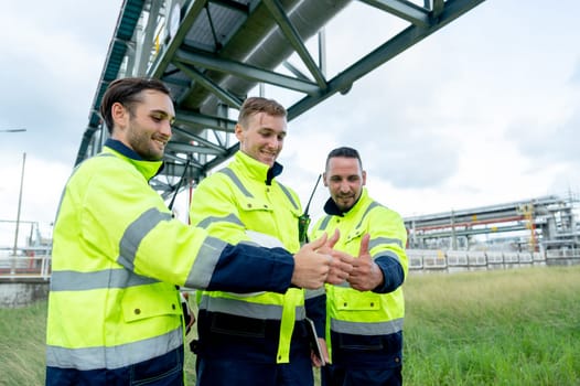 Factory engineer or technician workers stand with show thumbs up together stay under petrochemical pipeline with day light.