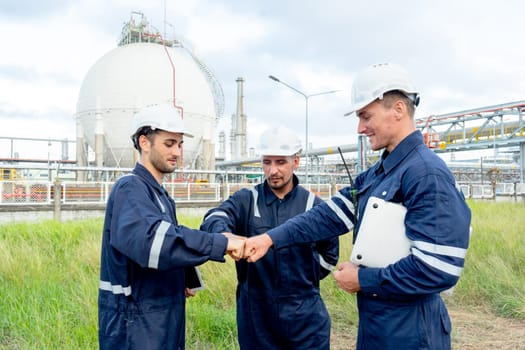 Group of engineer or technician workers stand in front of tank in petrochemical factory and they action of first bump.