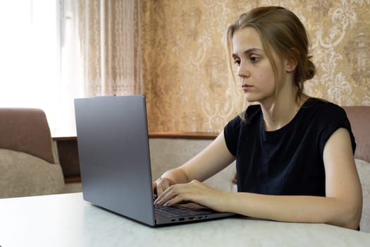 Focused young woman engages with her laptop in domestic workspace, showcasing her concentration and commitment