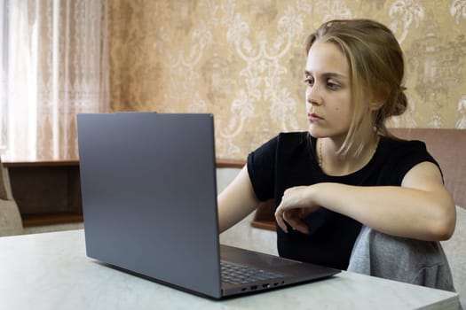Tired girl works on laptop from home, online learning and work in modern world for people working at home in comfortable environment