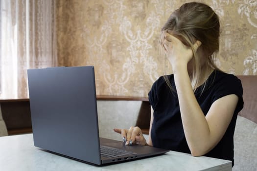 Girl is tired of working on laptop and falls asleep leaning on her arm, working on laptop from home, online learning and remote work causes lot of stress for girl worker