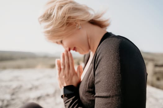 A woman with blonde hair is seen in a close-up, with her hands clasped in prayer, conveying a sense of peace and devotion.