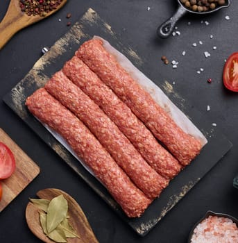 Raw lula kebab sausages on a board and spices, top view