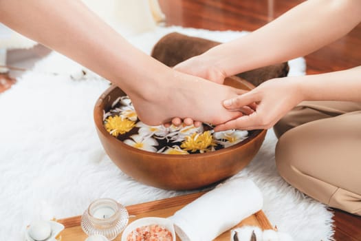 Woman indulges in blissful foot massage at luxurious spa salon while masseur give reflexology therapy in gentle day light ambiance resort or hotel foot spa. Quiescent