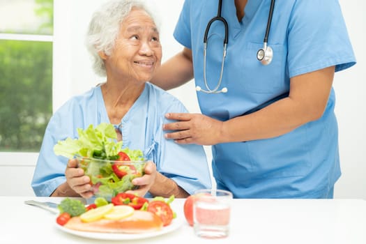 Asian elderly woman patient eating salmon steak breakfast with vegetable healthy food in hospital.