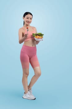 Young sporty Asian woman in sportswear holding salad bowl fill with vibrant of fruit and vegetable. Natural youthful and fit body lifestyle with balance nutrition on isolated background. Vigorous