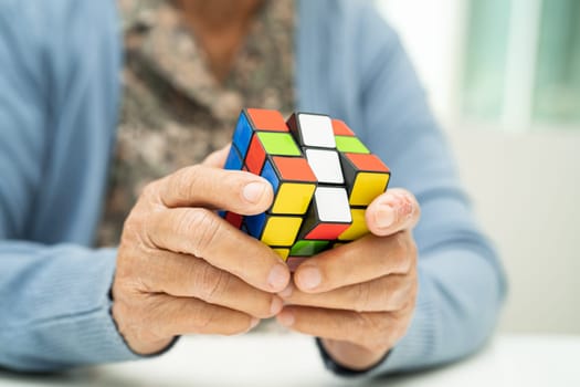 Bangkok, Thailand August 14, 2023 Alzheimer disease AD, Asian elderly woman patient playing Rubik cube game to practice brain training for dementia prevention.