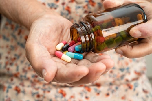 Asian senior woman patient holding antibiotics capsule pills  for treatment infection patient in hospital, Pharmacy drugstore concept.