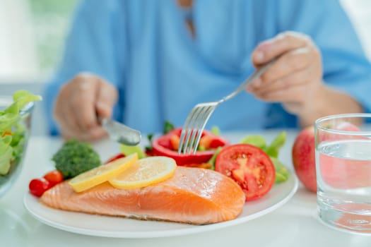 Asian elderly woman patient eating salmon steak breakfast with vegetable healthy food in hospital.