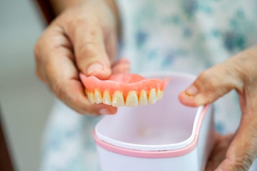 Asian elderly woman patient holding to use denture, healthy strong medical concept.