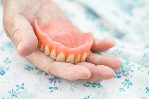 Asian elderly woman patient holding to use denture, healthy strong medical concept.