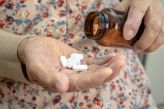 Asian senior woman patient holding antibiotics capsule pills  for treatment infection patient in hospital, Pharmacy drugstore concept.