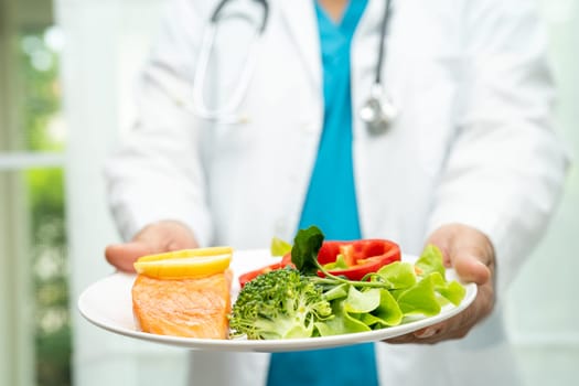 Nutritionist doctor holding healthy salmon steak and vegetable vitamin food for patient in hospital.