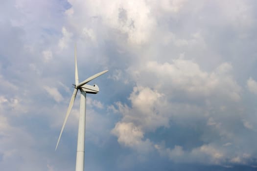 Windmill for power generation, against an overcast sky, view from below.