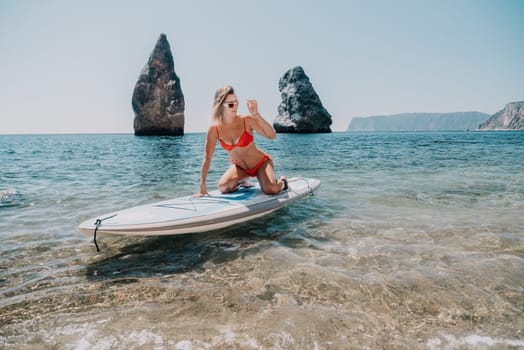 Close up shot of beautiful young caucasian woman with black hair and freckles looking at camera and smiling. Cute woman portrait in a pink bikini posing on a volcanic rock high above the sea