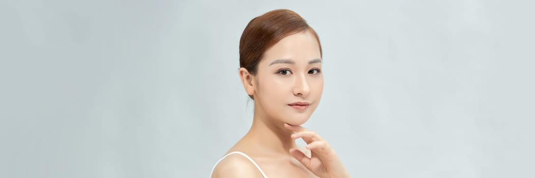 Youthful pretty Asian woman with hand touching face on white background for web banner