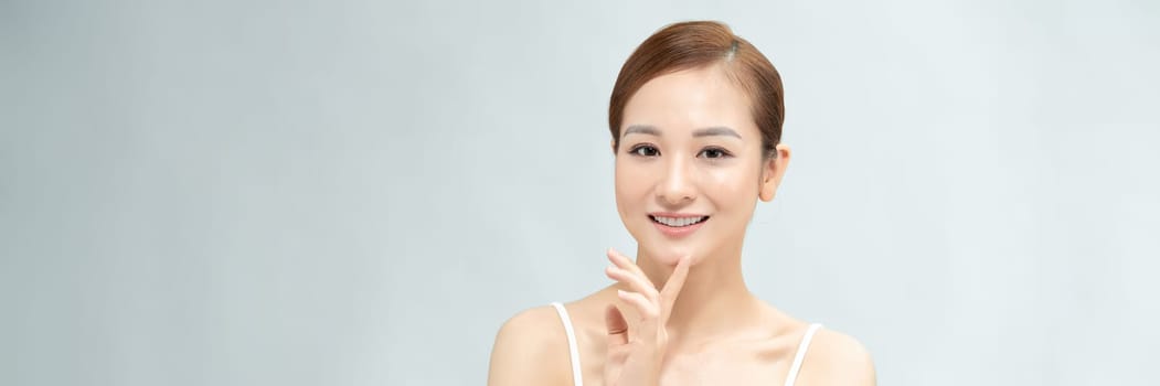 Youthful pretty Asian woman with hand touching face on white background for web banner