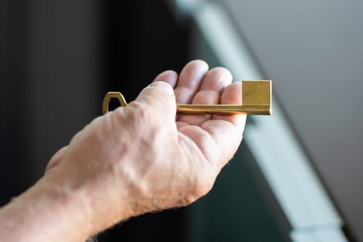 Man hand holding new home key brown colour. High quality photo