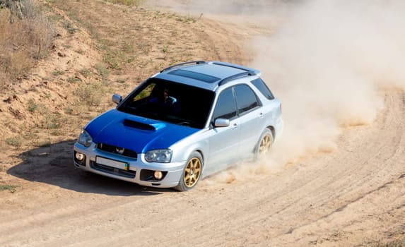 Sunny summer day. Rally hatchback during a sharp turn on a dirt track