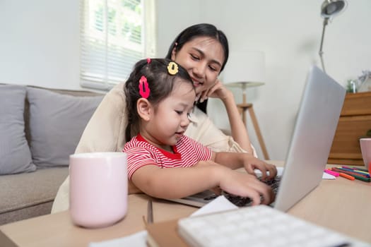 A mother and daughter sharing a moment while using a laptop, symbolizing teaching and learning at home. Ideal for concepts of family bonding and education.