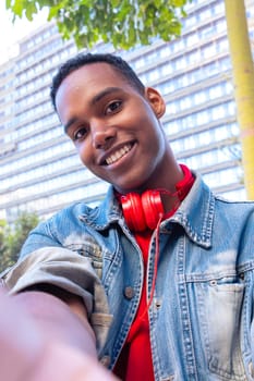 A happy student with headphones on the university campus taking a self-portrait to upload to a social media app