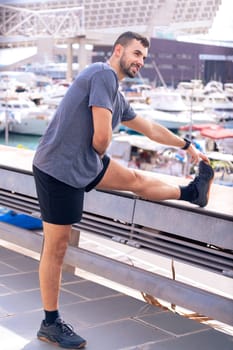 Young sportsman with concentrated sports watch stretching before training outdoors.Vertical