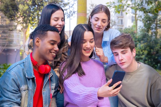 Group of friends using looking at their smartphones Multiracial teenagers browsing the internet with mobile phone on campus