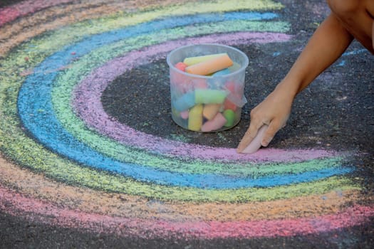 the boy draws with chalk on the asphalt. Selective focus.