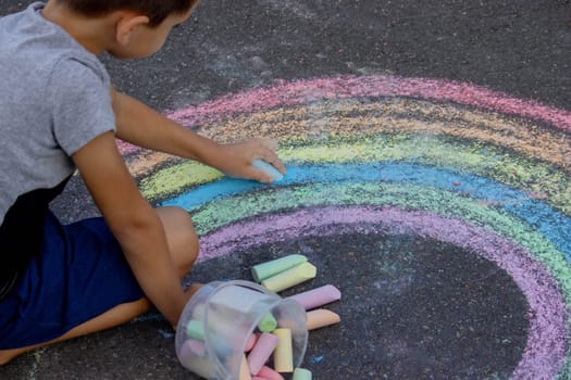 the boy draws with chalk on the asphalt. Selective focus.