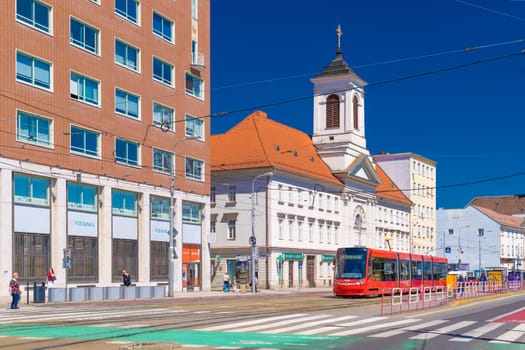 Bratislava, Slovakia - 14 May 2024: A red tram pases in front of the Church of St. Ladislaus