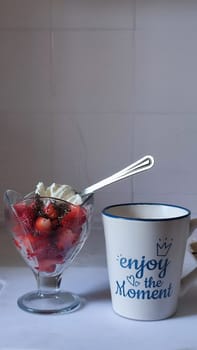 03 April 2024 Beer-Sheva Israel, home kitchen, cup with the inscription Enjoy the moment, vase with strawberries fruit food. High quality editorial photo