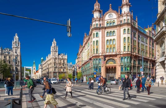 Budapest, Hungary - 5 April 2024: People cross the road near the Parisi Udvar Hotel, art nouveau architecture.