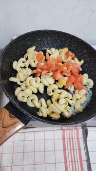 boiled pasta with tomatoes in a frying pan, healthy food, breakfast cooking lunch. High quality photo
