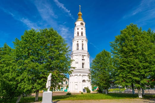 The bell tower of the Holy Trinity Church and a monument of Alexander Pushkin in a small Russian town of Lezhnevo