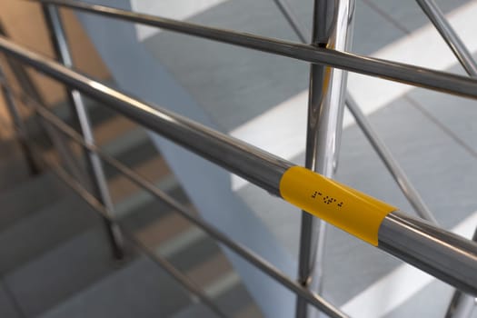 Support blind people on stairs with braille text for help on way. Accessible area for people with disabilities. Modern handicapped care sign with braille text on railings