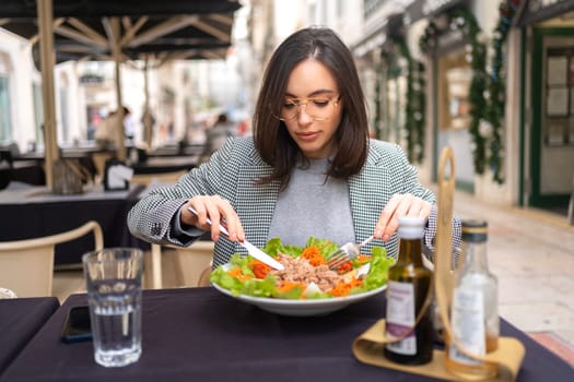 Stylish business woman eating healthy salad on restaurant terrace, feeling happy on summer day