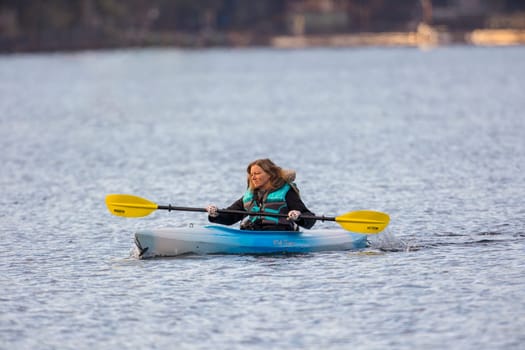 A woman kayaker enjoys a nice but chilly day paddling on Coeur d'Alene, lake in north Idaho.