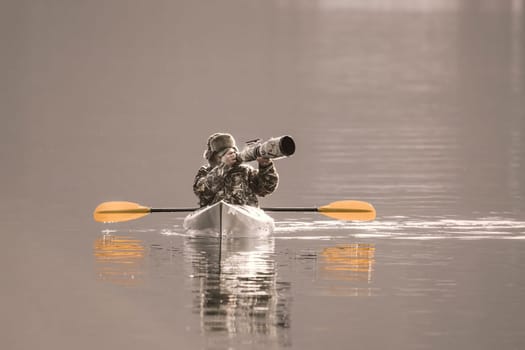A photographer is out in his kayak taking pictures with his large camera and lens on the lake in Coeur d'Alene, Idaho.