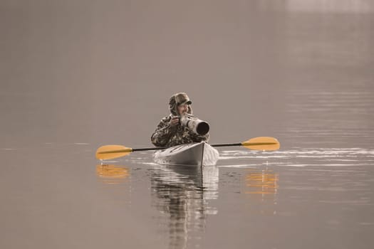 A photographer is out in his kayak taking pictures with his large camera and lens on the lake in Coeur d'Alene, Idaho.