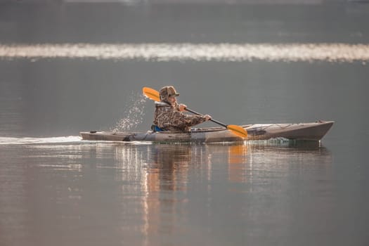 A man is paddling his kayak in chilly weather on Coeur d'Alene Lake in north Idaho.