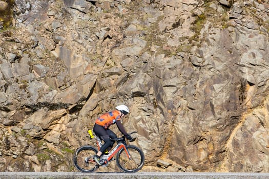 A man is riding a bike on a country road next to a rock wall in Coeur d'Alene, Idaho.