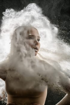 Young model in a beige bodysuit in a cloud of white dust studio shot