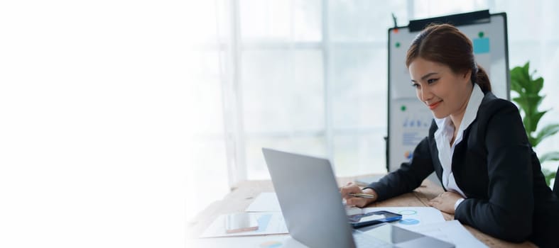 woman meticulously plans a finance audit, using a computer and calculator to review budget documents and ensure accuracy.