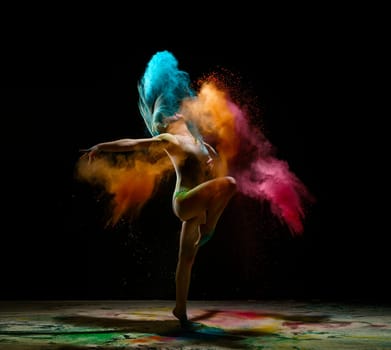 Young model in a cloud of color dust studio shot on black background