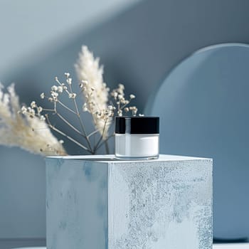 Cosmetic cream in a glass jar on a blue backdrop. Skin care concept. Background for beauty products
